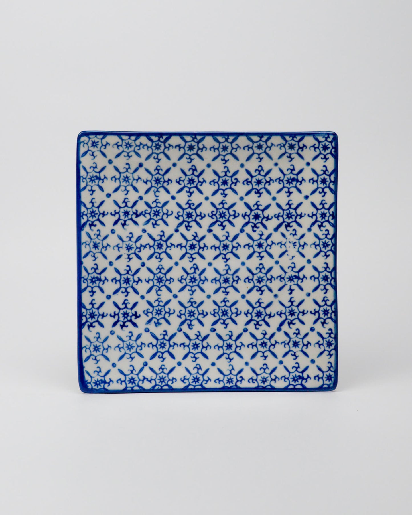 Square ceramic plate with blue and white geometric pattern on a white background