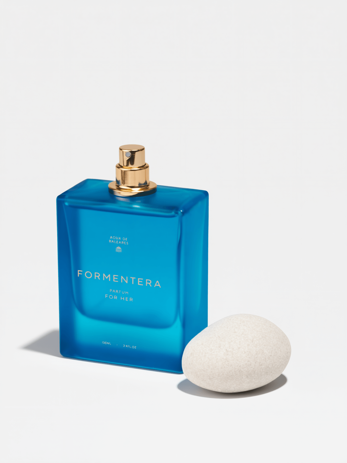 A blue rectangular Formentera perfume bottle with a gold spray top, shown next to a white textured stone on a clean white background.