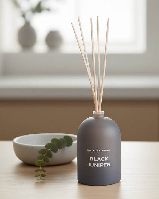 Smoke Grey diffuser bottle labeled 'Black Juniper' on a table with a blurred background
