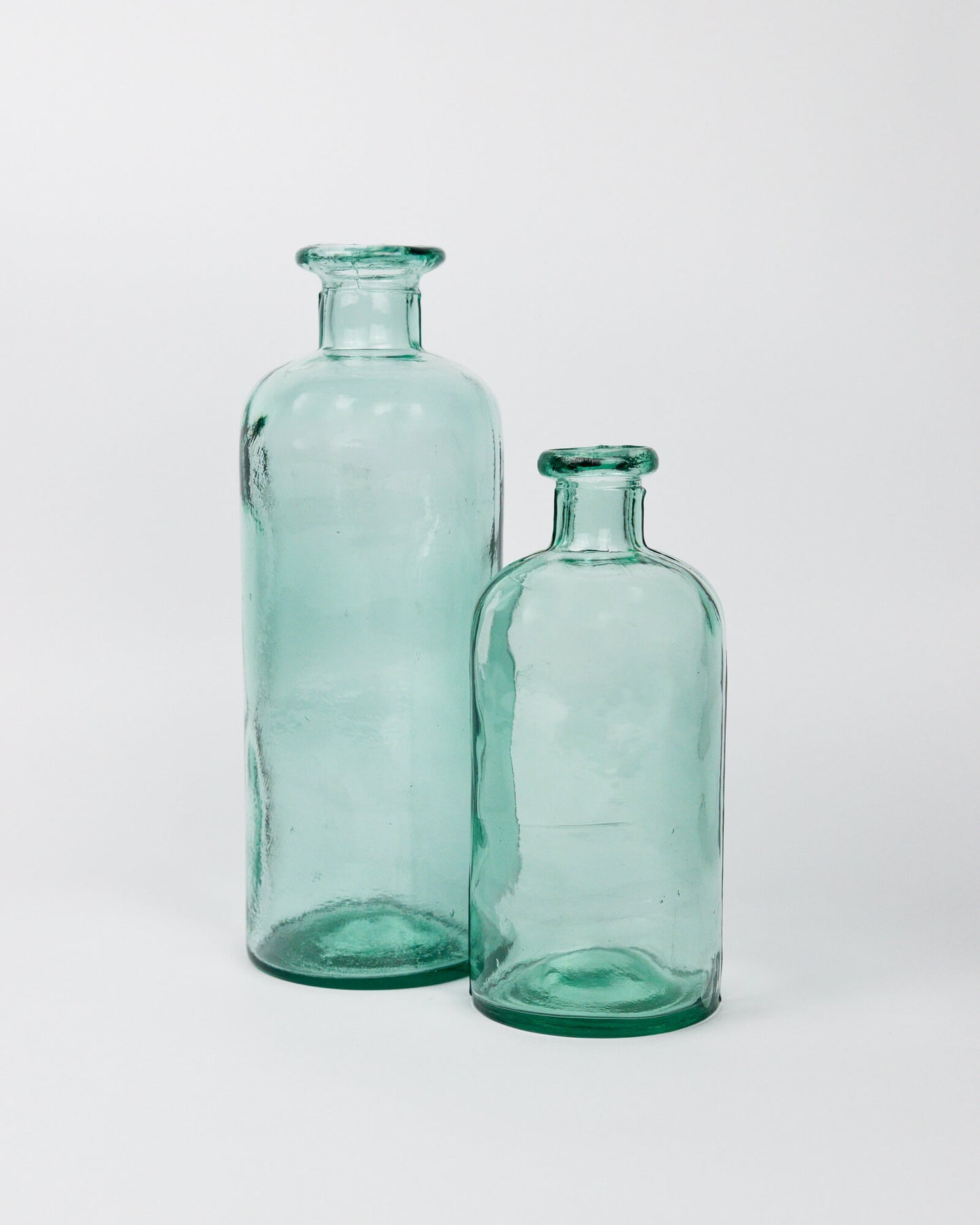 Two green glass bottles on a white background