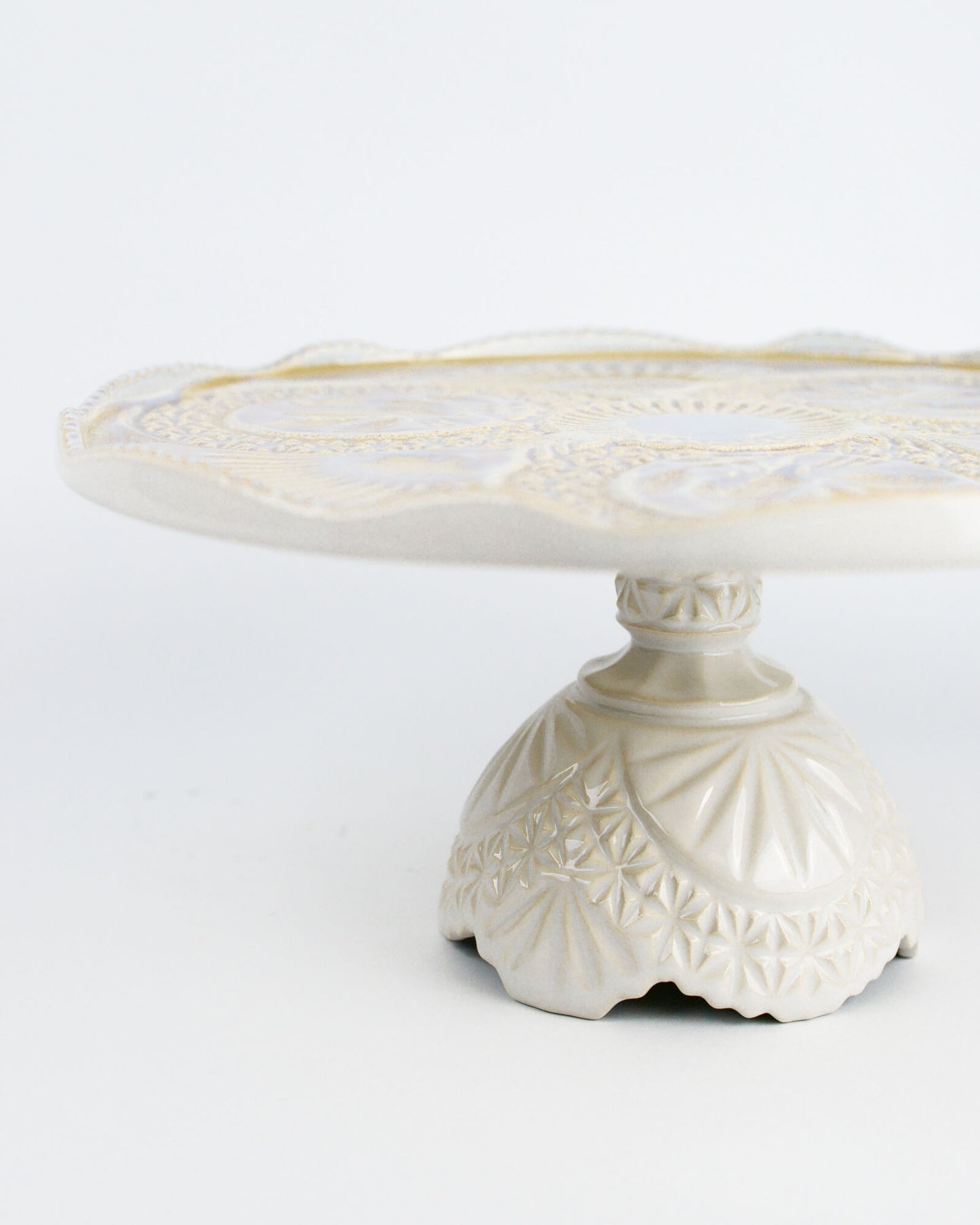 Decorative white cake stand with intricate patterns on a white background