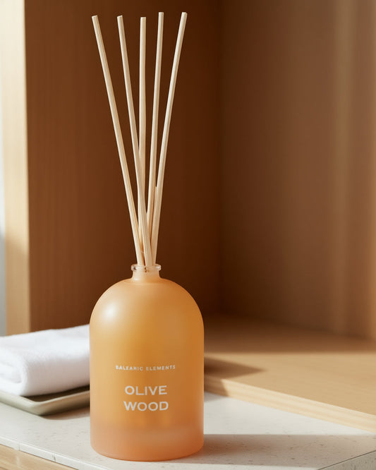 Orange diffuser bottle with wooden sticks on a neutral background