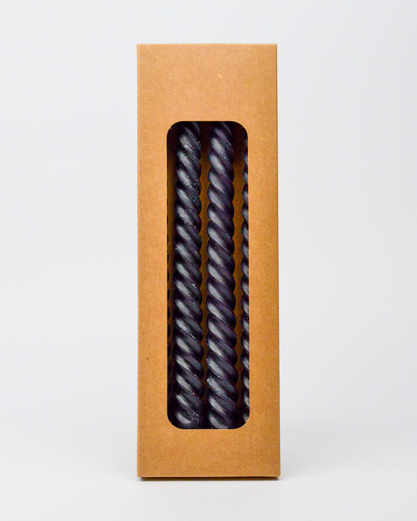Kraft paper box with a window displaying twisted black taper candies on a white background