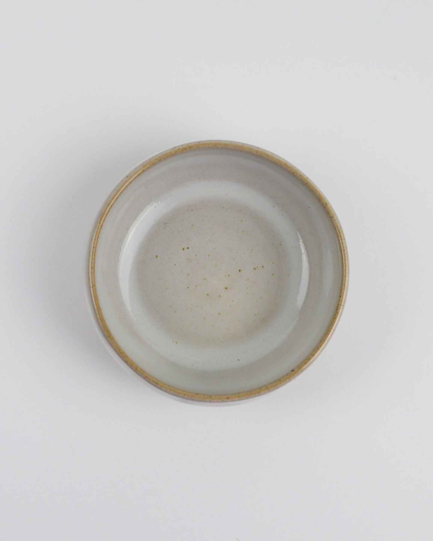 Ceramic dipping bowl with a textured rim on a white background