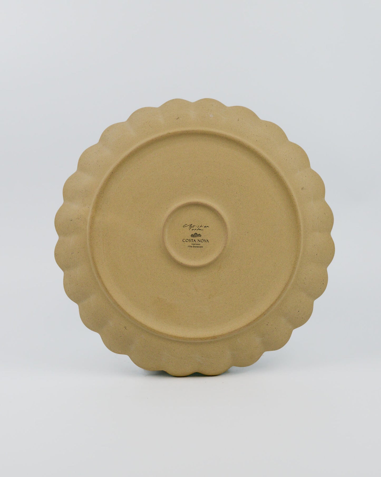 Stoneware plate with scalloped edge on a white background