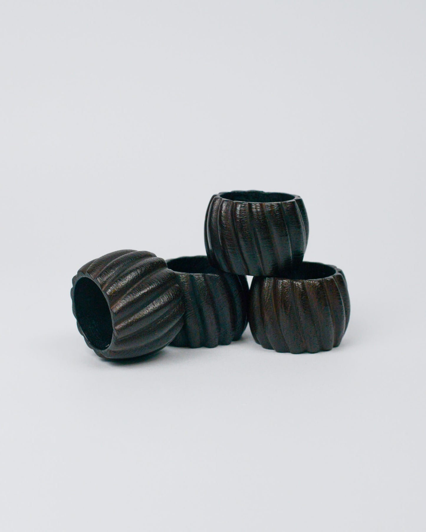 Set of four dark wooden ribbed napkin ring on a white background