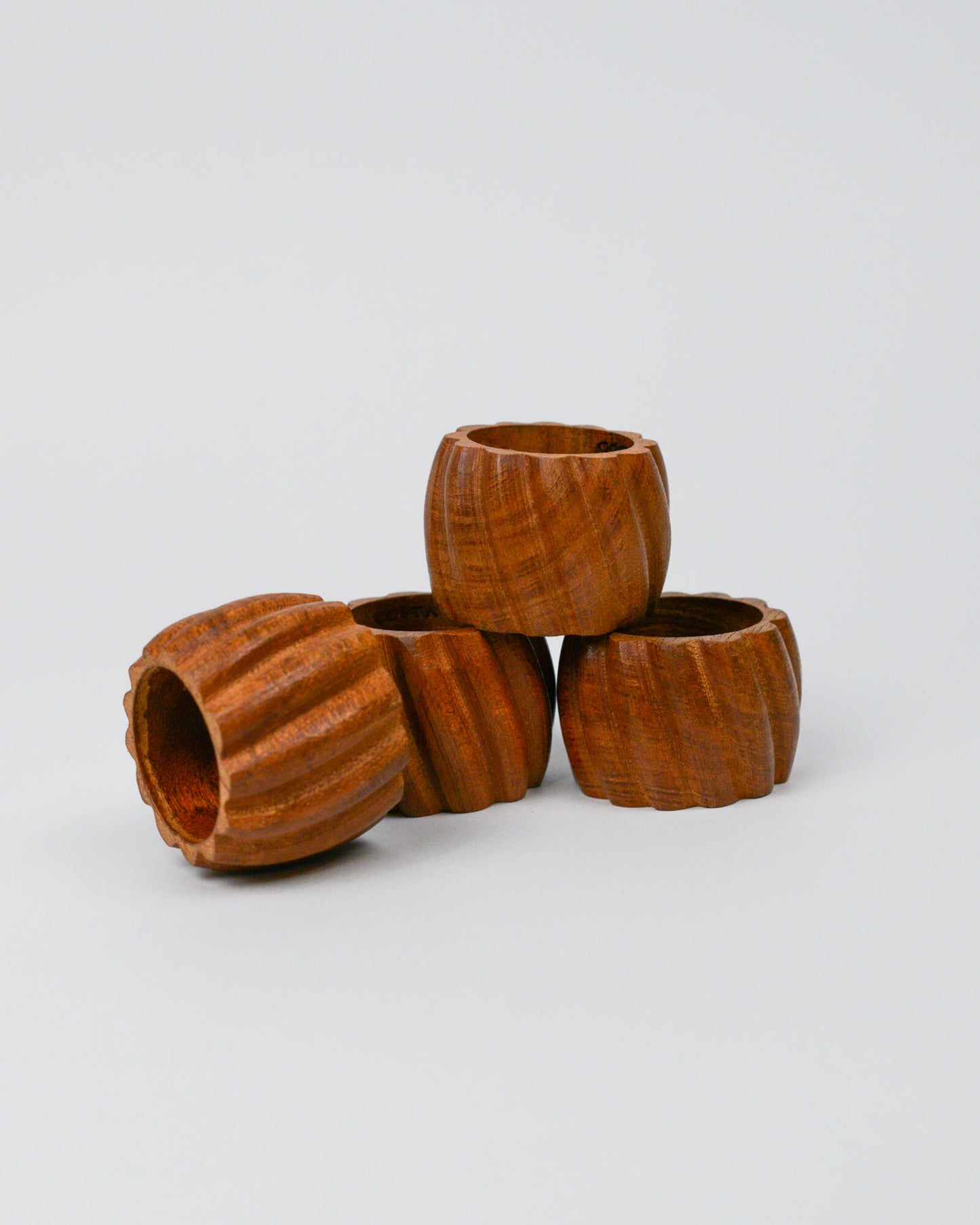 Stack of four wooden carved napkin rings on a white background