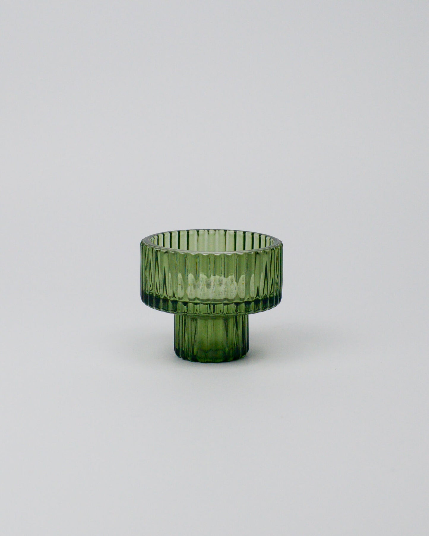 Green glass tealight candle holder on a white background
