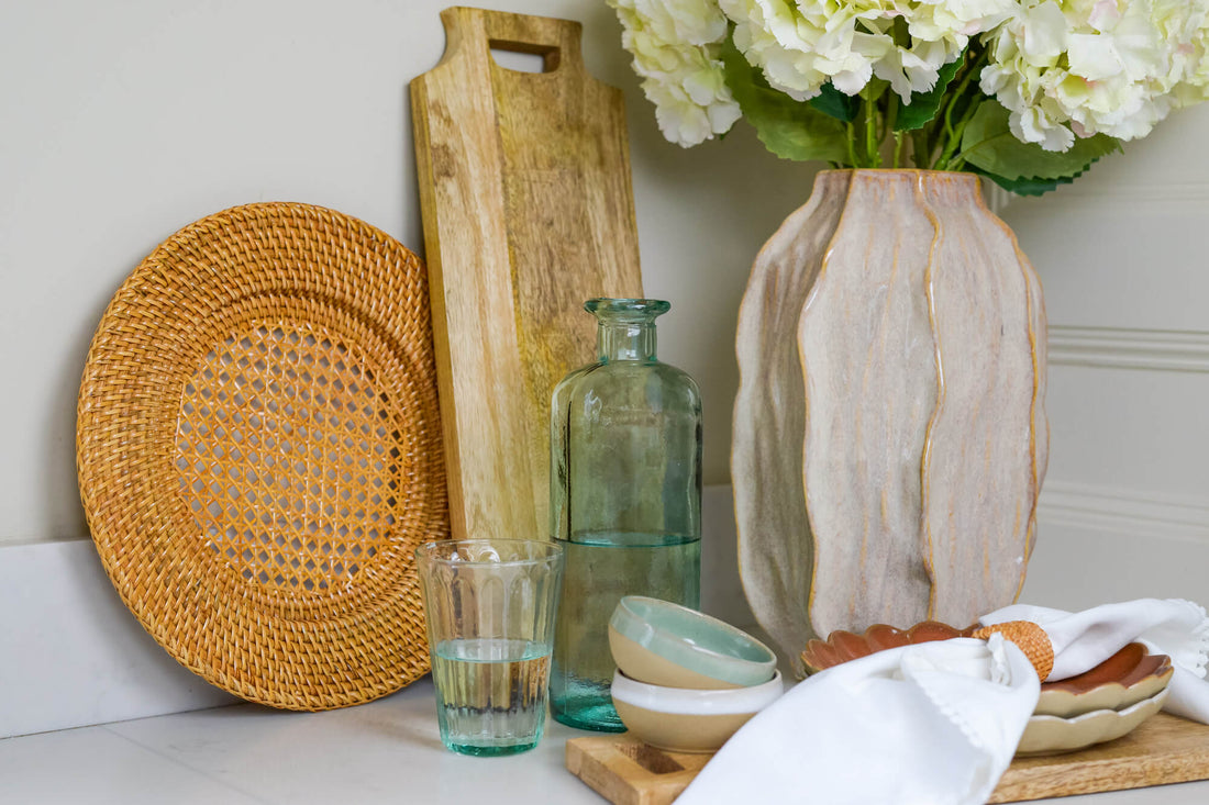 Marble worktop corner with rattan charger plate, decorative scalloped edge plates and a decorative vase holding white flowers