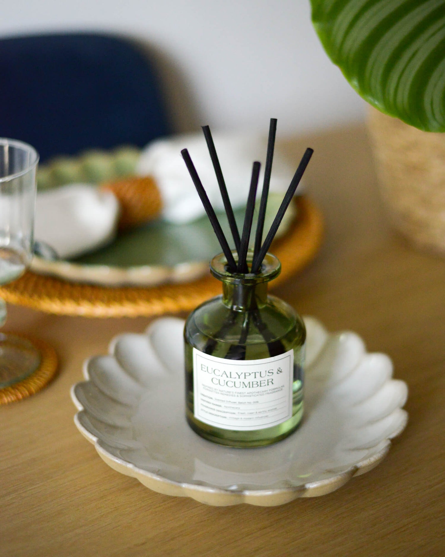 Green, glass Eucalyptus and Cucumber reed diffuser on a scalloped edge white plate