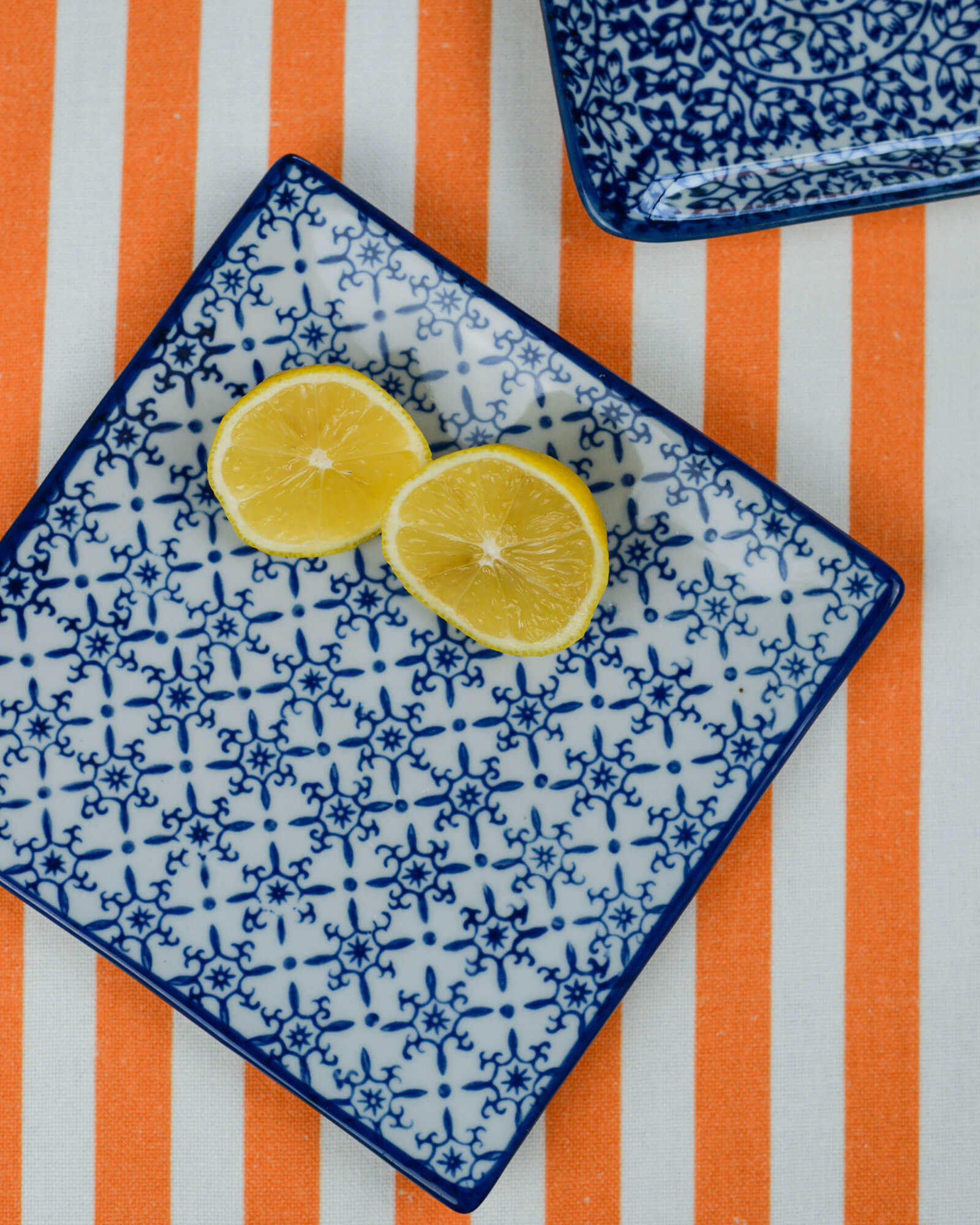 Blue patterned plate with lemon slices on an orange and white striped tabe runner