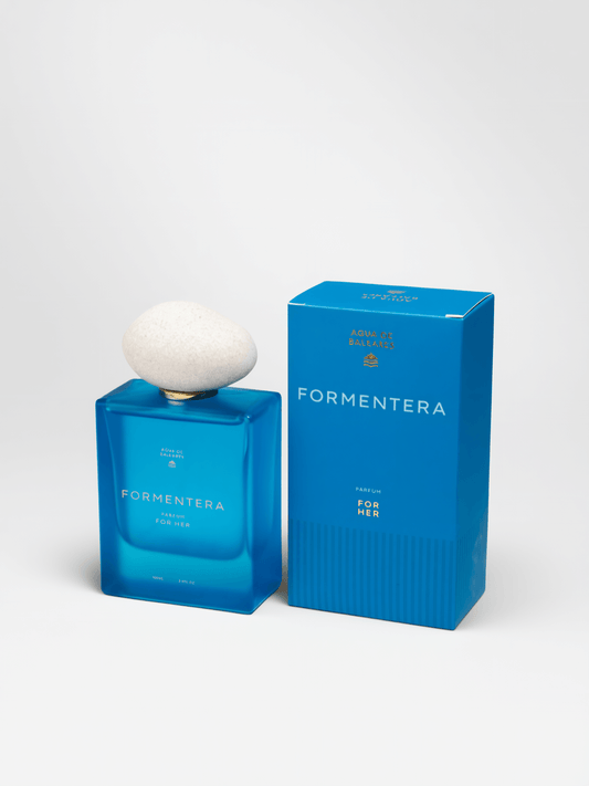 A blue rectangular perfume bottle with a white rounded cap stands next to its matching blue box on a white studio background. The bottle and box are labeled FORMENTERA.