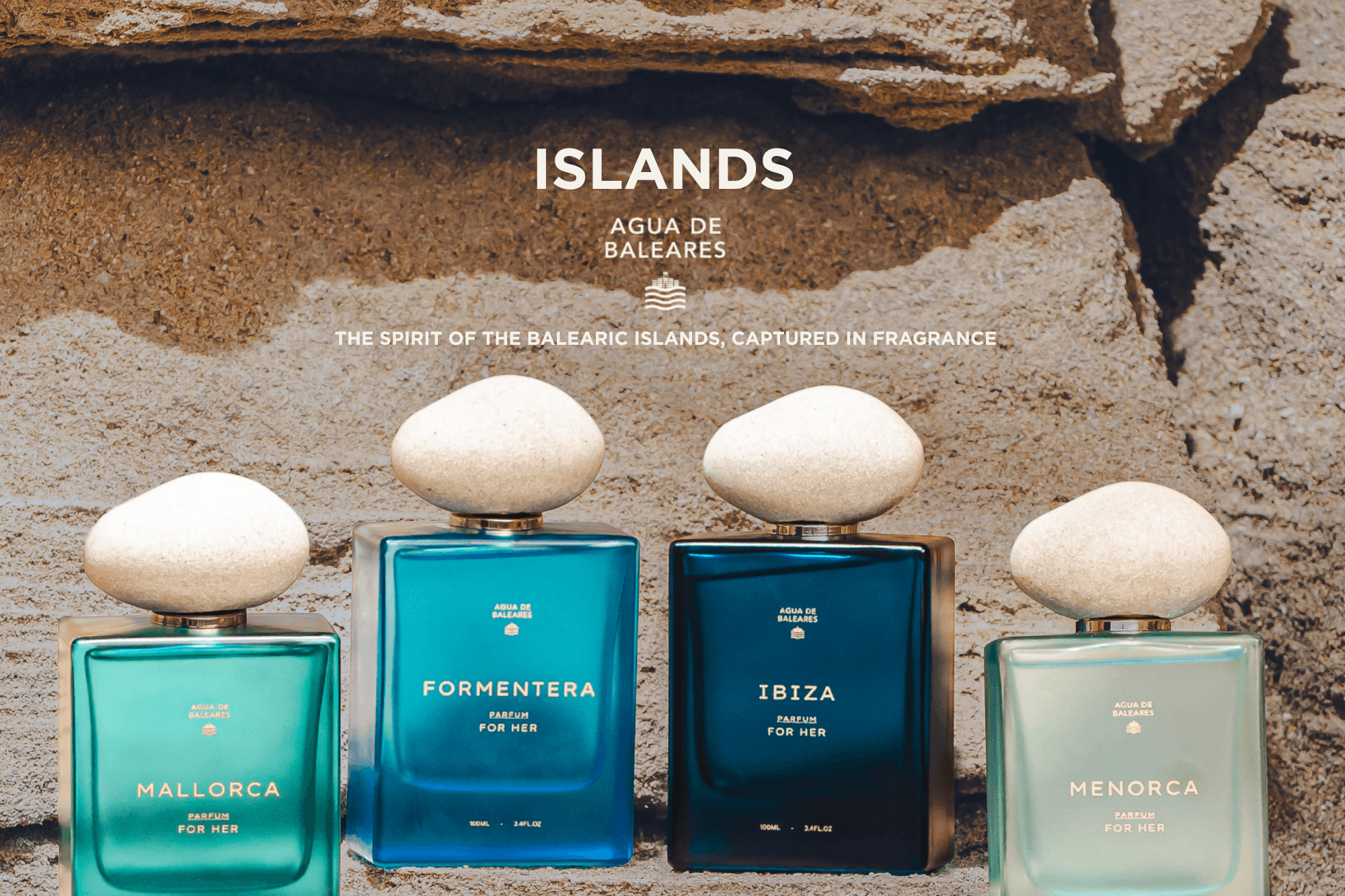 Four rectangular fragrance bottles with rounded white caps are arranged against a textured stone wall. The bottles are in different blue-green shades and labeled with island names: Mallorca, Formentera, Ibiza, and Menorca.