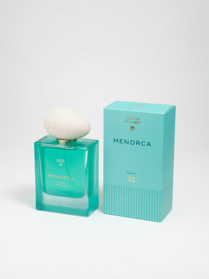 A turquoise glass perfume bottle with a white rounded cap stands beside its matching turquoise box on a clean white studio background. The bottle and box both show the brand name MENORCA.