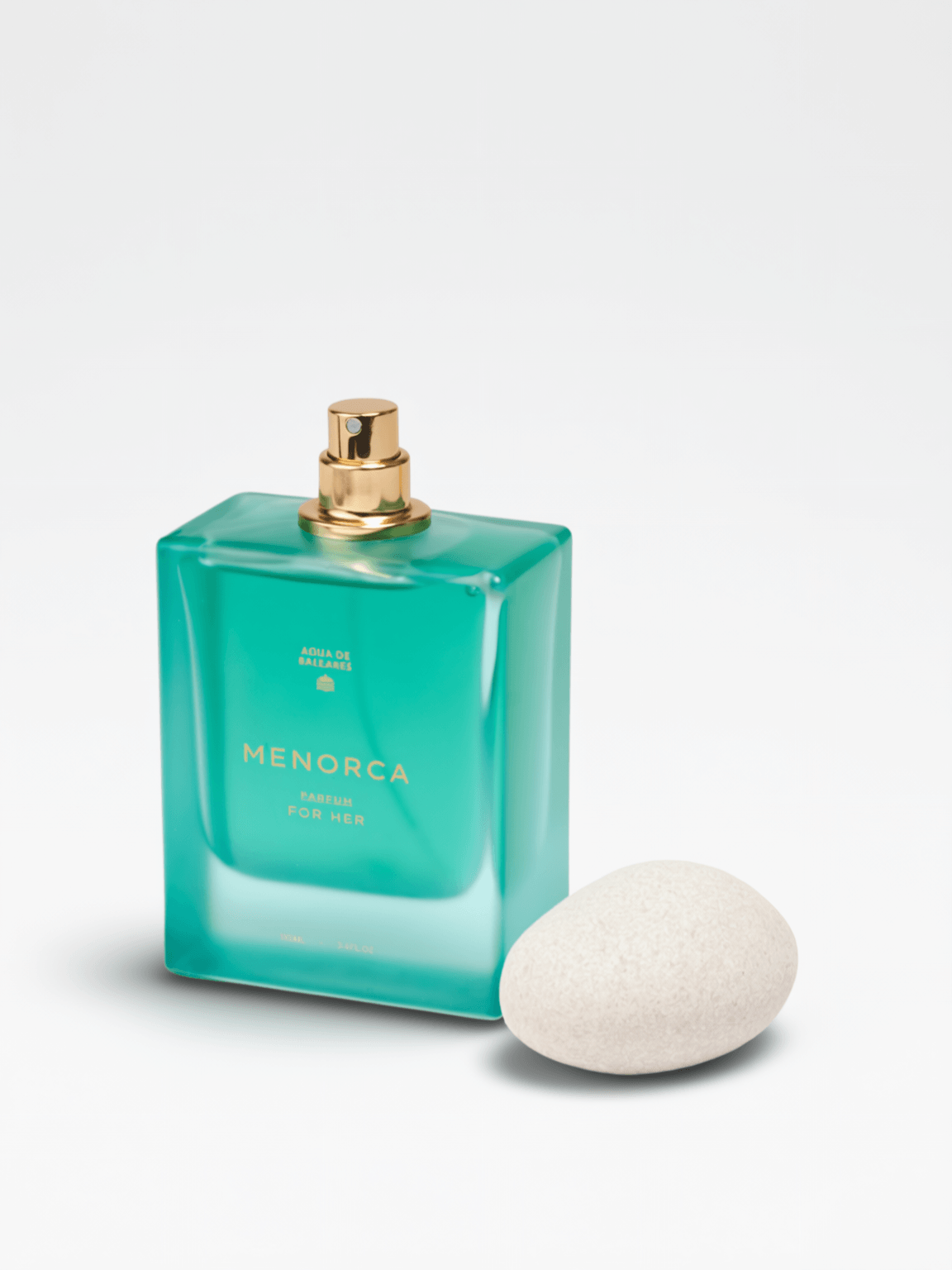 A turquoise glass perfume bottle with a white rounded cap stands on a clean white studio background. The bottle shows the name MENORCA.