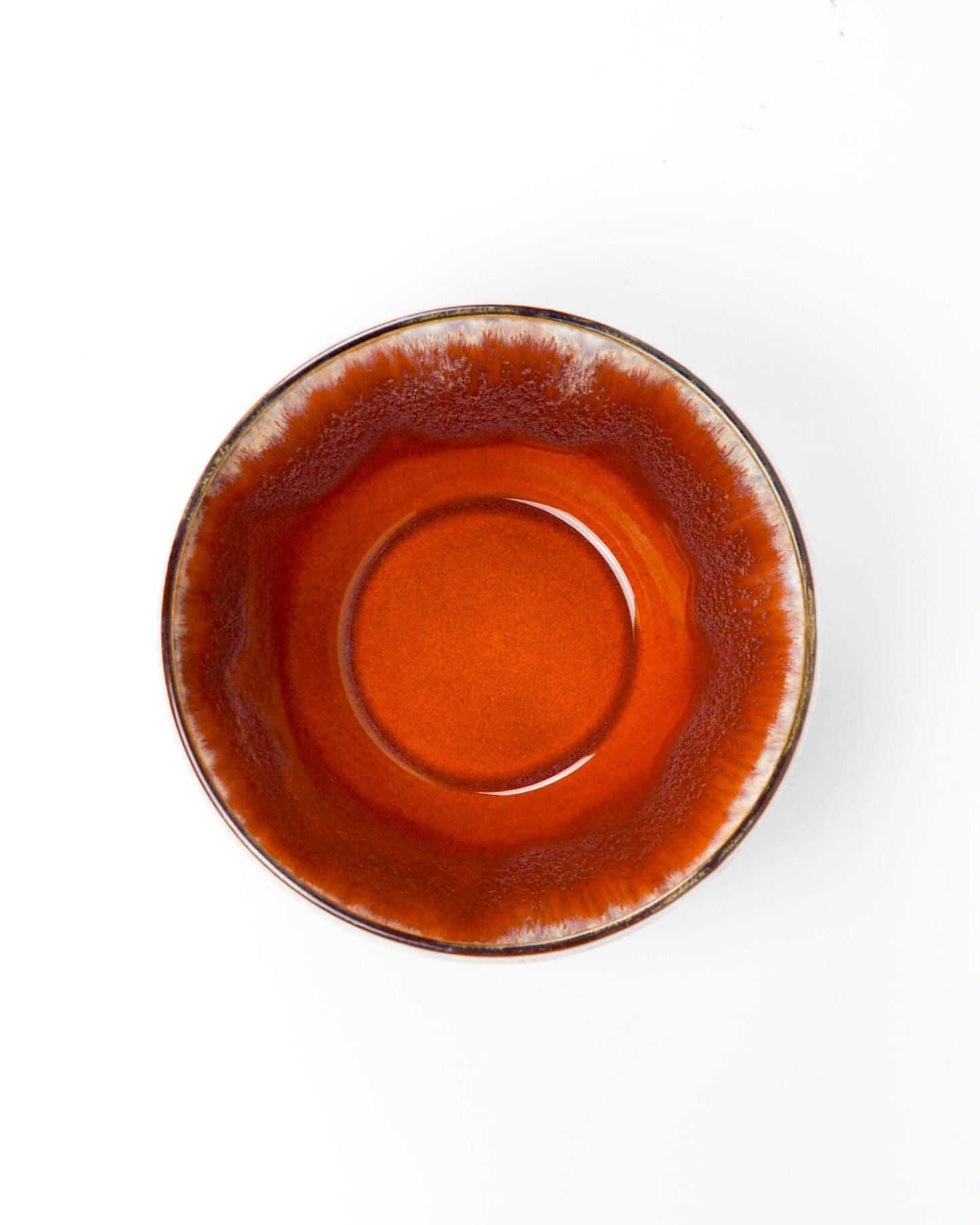 Arial shot of a ceramic serving bowl with a burnt orange and beige glazed rim on a white background