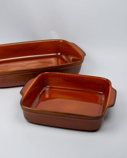 Two burnt orange ceramic baking dishes on a white background similar in style to le cruset