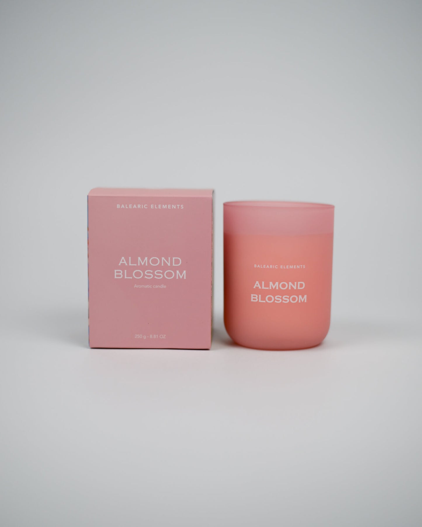 Pink 'Almond Blossom' scented candle and packaging on a white background