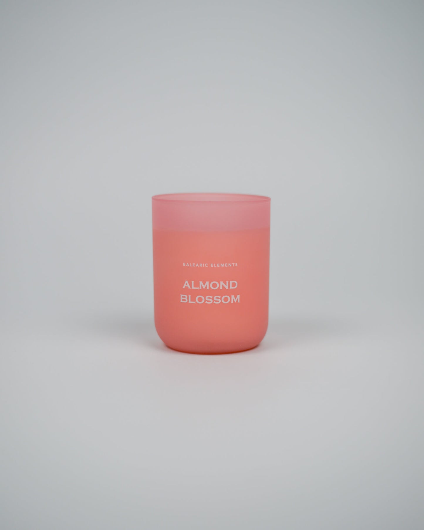 Pink scented candle labeled 'Almond Blossom' on a white background