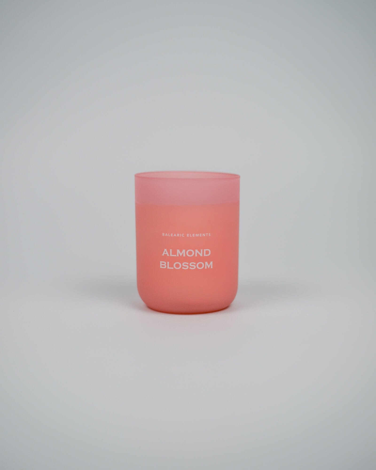 Pink scented candle labeled 'Almond Blossom' on a white background