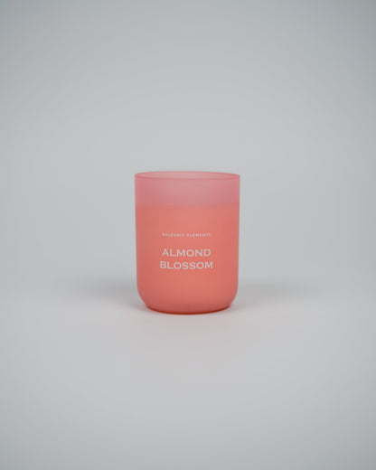 Pink scented candle labeled 'Almond Blossom' on a white background