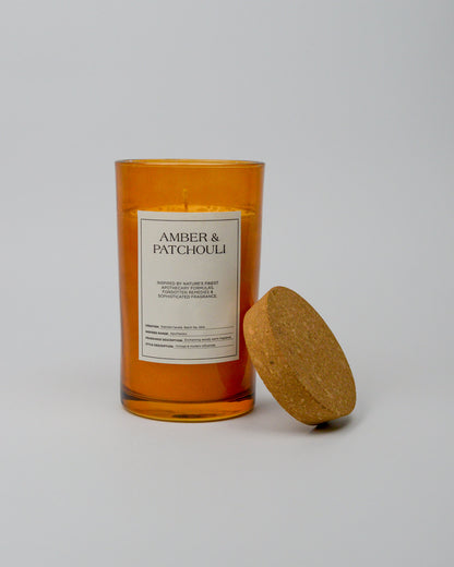 Candle with amber and patchouli scent and cork lid on a white background