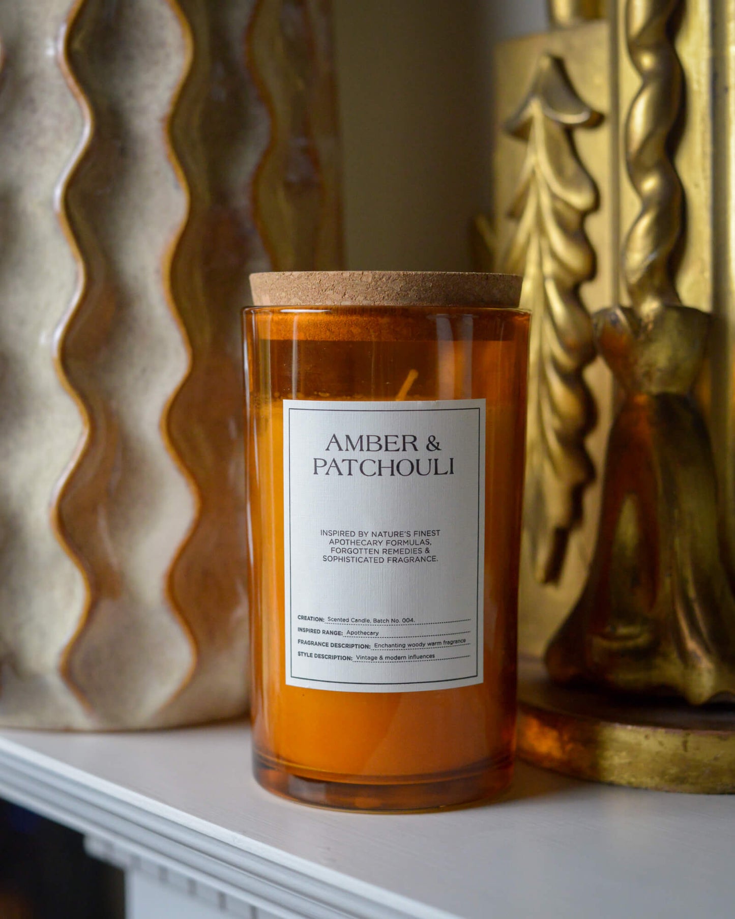 Candle labeled 'Amber & Patchouli' with decorative background