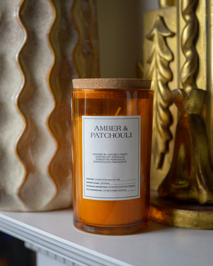 Candle labeled 'Amber & Patchouli' with decorative background