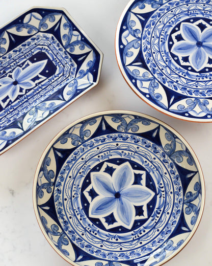 Three blue and white terracotta ceramic plates with intricate patterns on a marble surface.