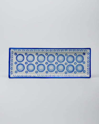 Rectangular ceramic plate with blue circular and floral pattern on a white background