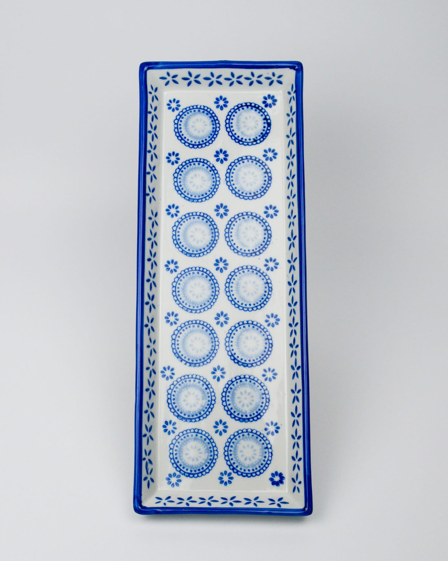 Rectangular ceramic tray with blue circular patterns on a white background