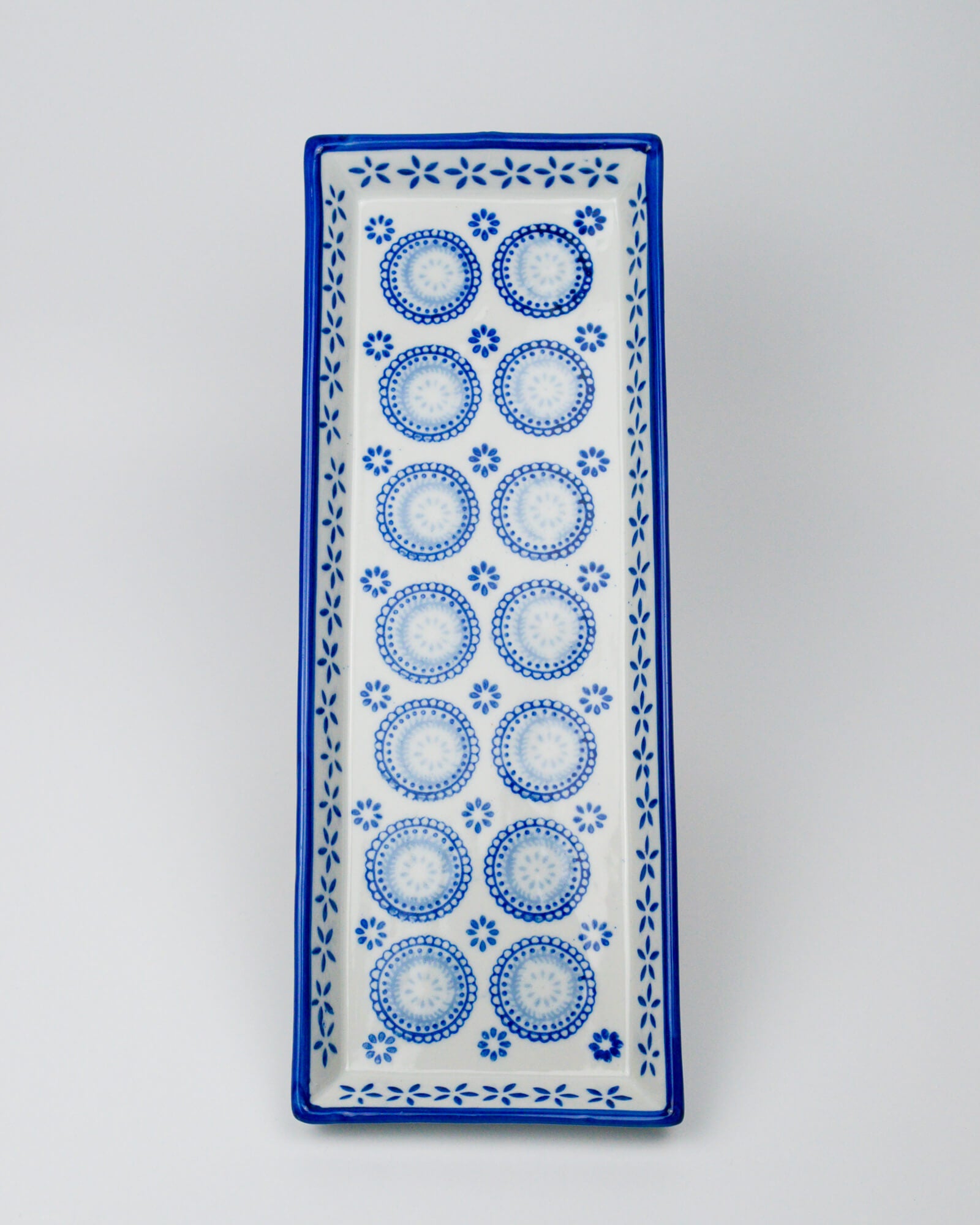 Rectangular ceramic tray with blue circular patterns on a white background