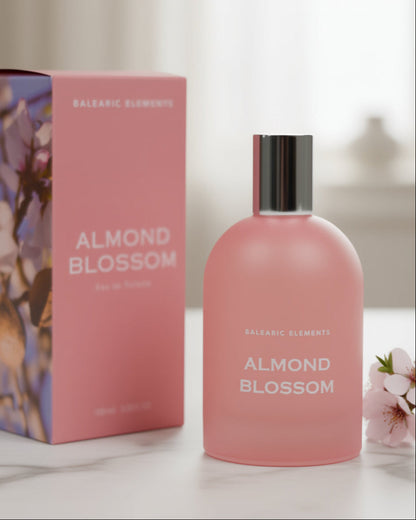 Pink 'Almond Blossom' perfume bottle and packaging on a light surface with a blurred background
