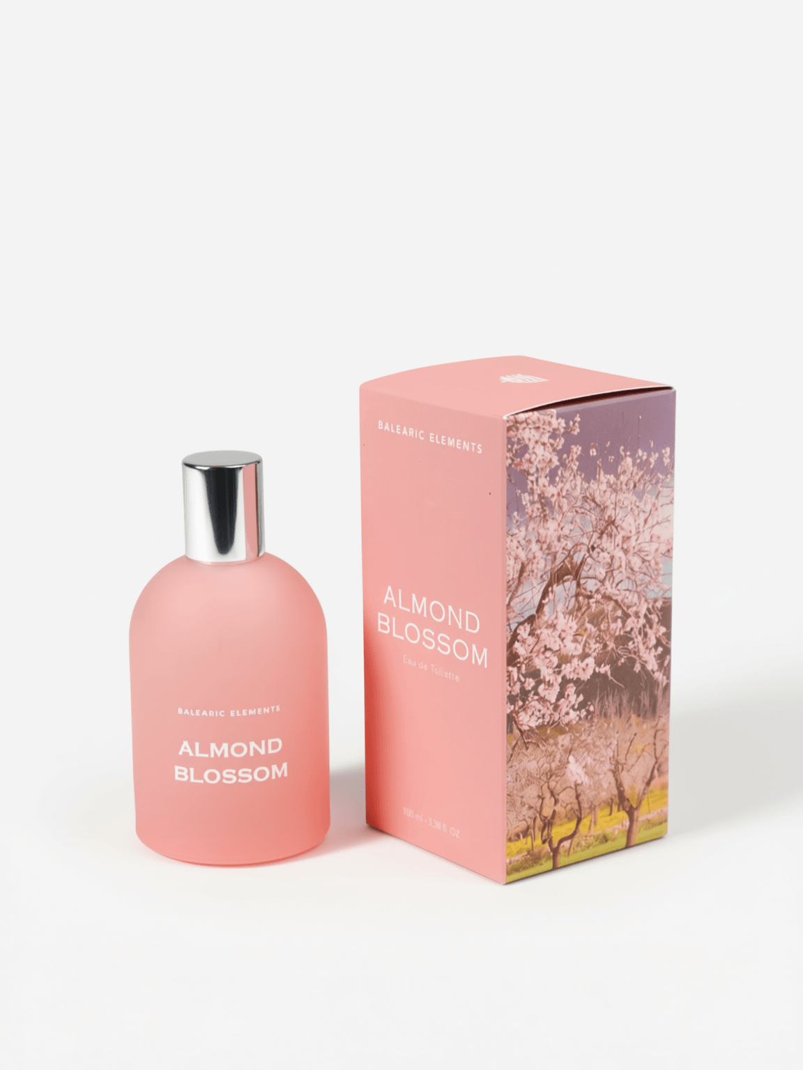 A pink perfume bottle with a silver cap stands next to its matching pink packaging box featuring a cherry blossom tree illustration. The text on both the bottle and box reads 'ALMOND BLOSSOM'.