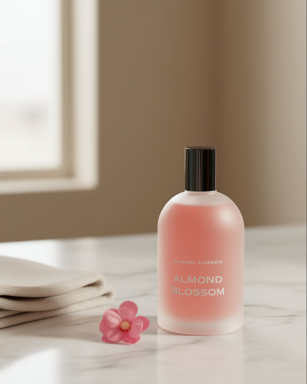 Pink bottle of 'Almond Blossom' perfume on a light surface with a pink flower and beige fabric.