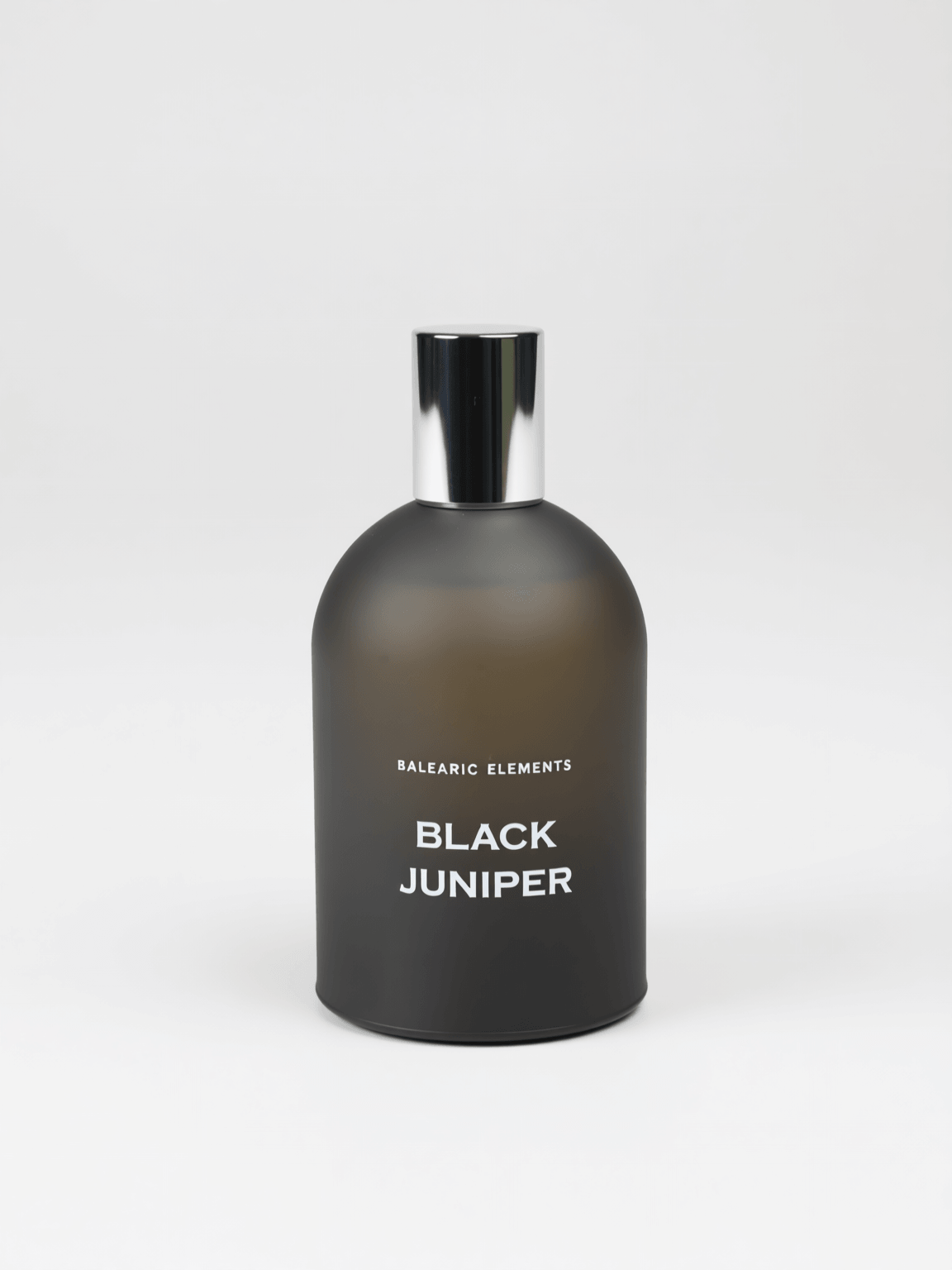 A matte black glass perfume bottle with a reflective silver cap, labeled 'BALEARIC ELEMENTS BLACK JUNIPER' in white text, set against a clean light gray background.