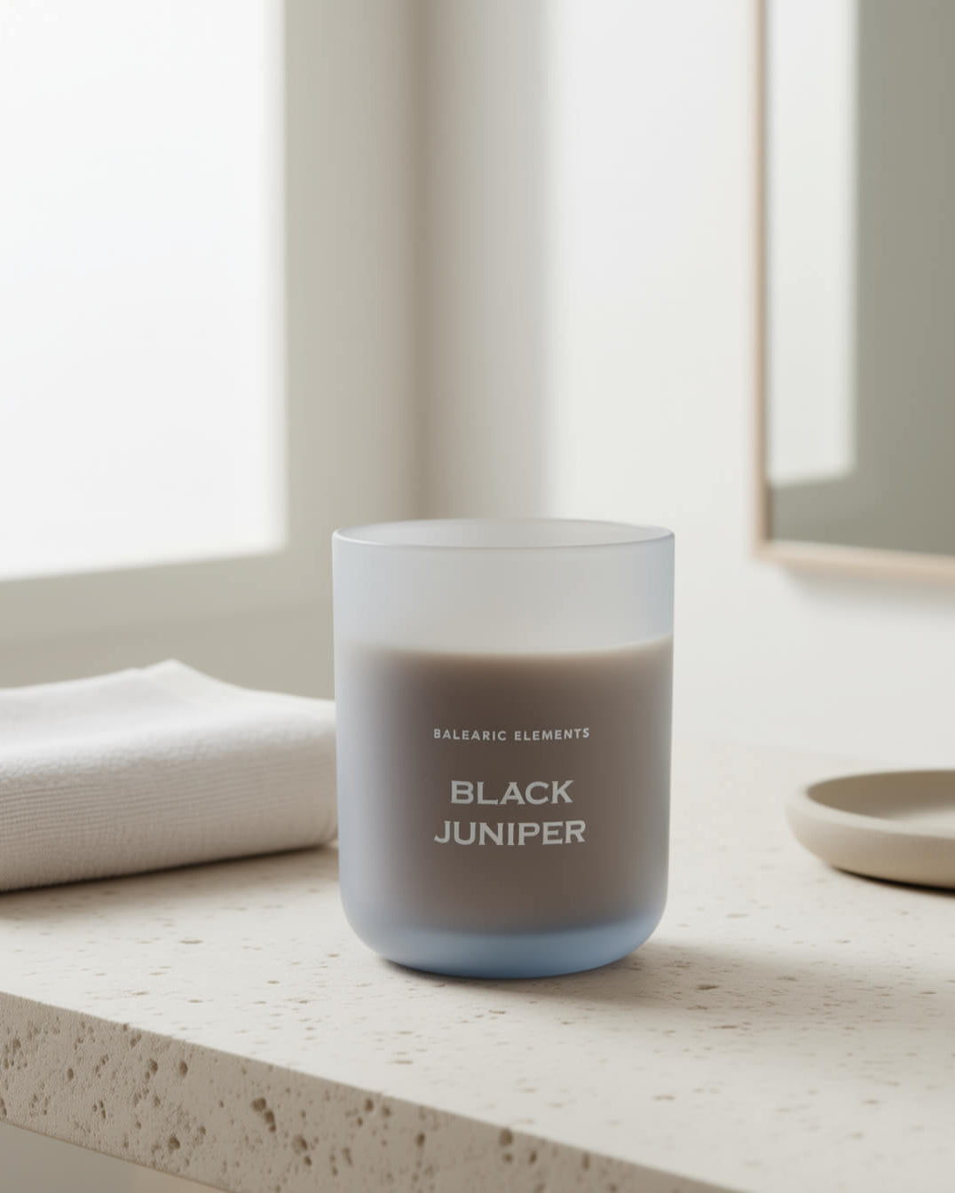 Candle labeled 'Black Juniper' on a light surface with neutral background