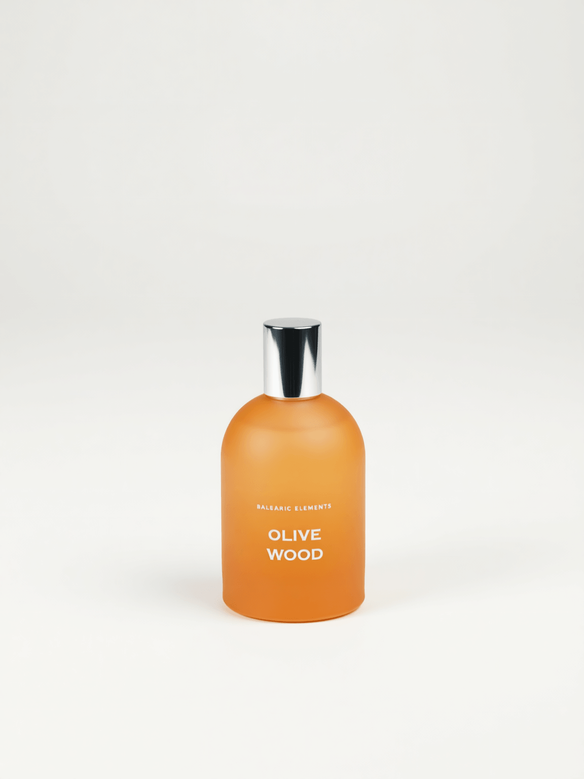 An orange frosted glass bottle with a shiny silver cap, labeled 'OLIVE WOOD' by Balearic Elements, set against a plain white background.