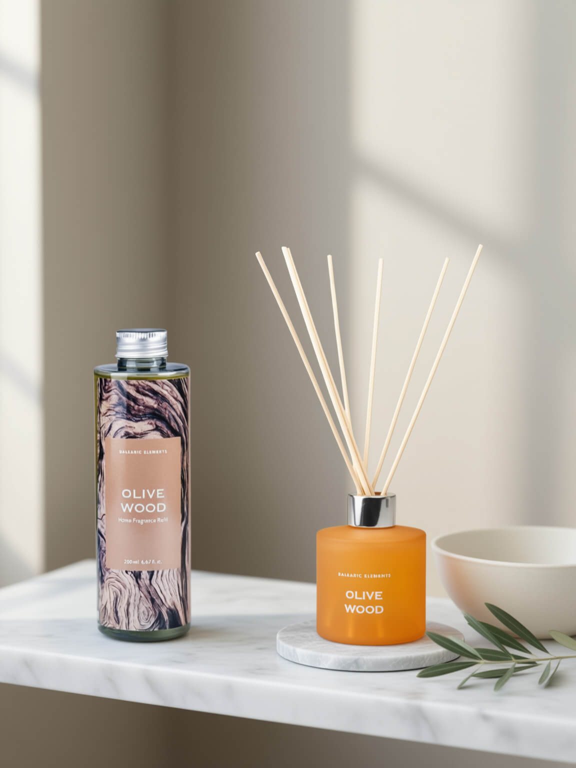 Olive Wood reed diffuser set by Beautifully Scented, featuring a patterned glass bottle and an amber glass reed diffuser bottle with wooden reeds, styled on a white marble surface next to a ceramic bowl.