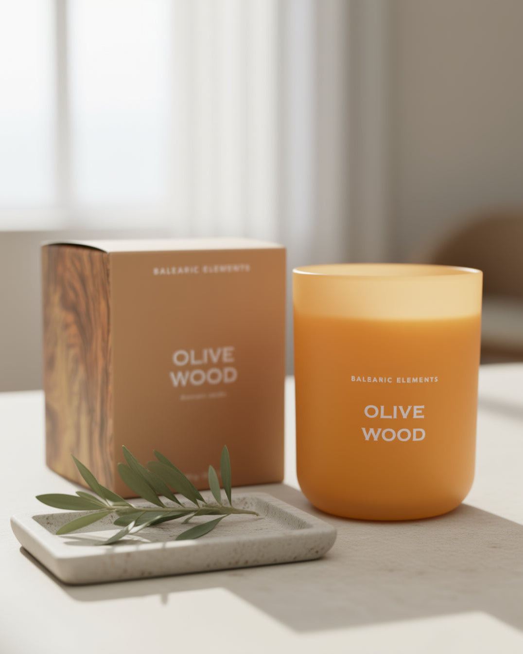 Olive wood scented candle with packaging and olive branch on a neutral background