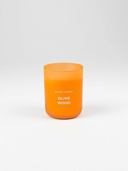 An orange frosted glass candle jar with white text reading 'OLIVE WOOD' on a clean white background.