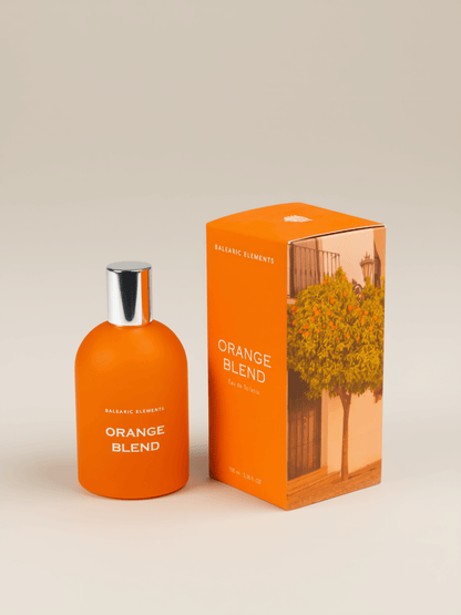 An orange perfume bottle labeled 'ORANGE BLEND' stands next to its matching orange packaging box on a warm beige studio background. The box features a printed image of an orange tree.