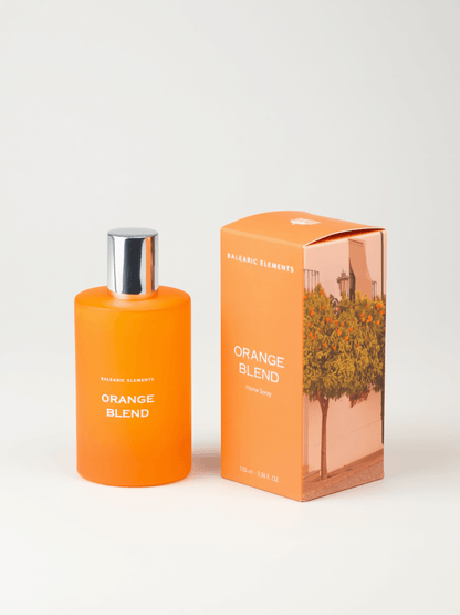 An orange perfume bottle with a silver cap stands next to its matching orange packaging box featuring an illustration of an orange tree. The text on both the bottle and box reads 'ORANGE BLEND' and 'BALEARIC ELEMENTS'.