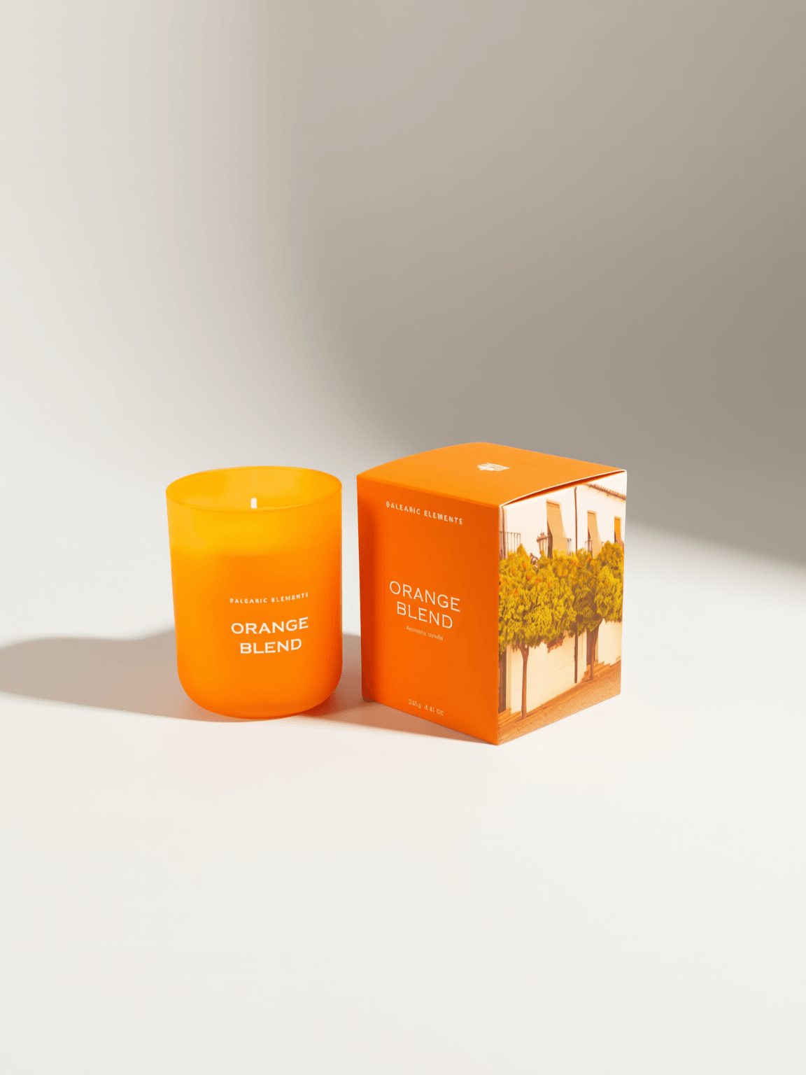 An orange glass jar candle labeled 'ORANGE BLEND' stands next to its matching orange packaging box on a clean white surface with soft shadows.