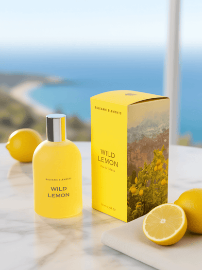 A bottle and box of Balearic Elements Wild Lemon perfume, styled on a marble surface with fresh lemons against a blurred coastal background.