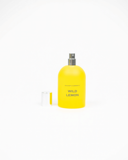 A bright yellow perfume bottle labeled 'WILD LEMON' with a silver spray top, shown on a clean white background with the cap placed to the left.