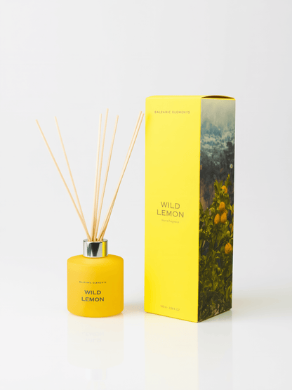 A reed diffuser bottle in bright yellow with natural reed sticks, standing next to its matching yellow packaging box featuring a lemon tree illustration, on a clean white background.