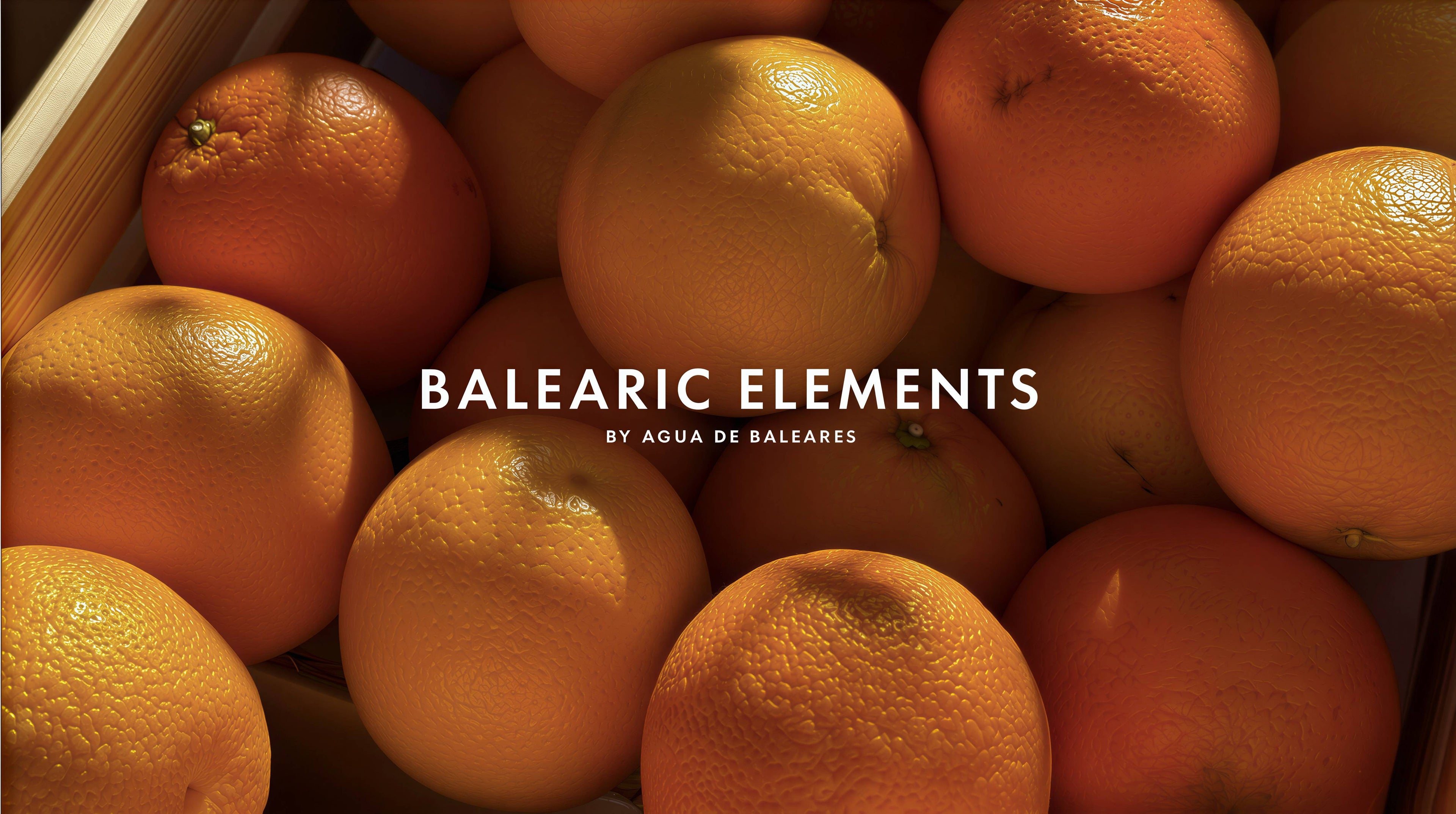 A close-up of many orange fruits in a wooden crate, with the text 'BALEARIC ELEMENTS' and smaller 'BY AGUA DE BALEARES' overlaid across the center.