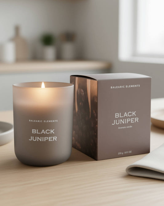 Smoke grey scented candle labeled 'Black Juniper' with its packaging on a wooden table.