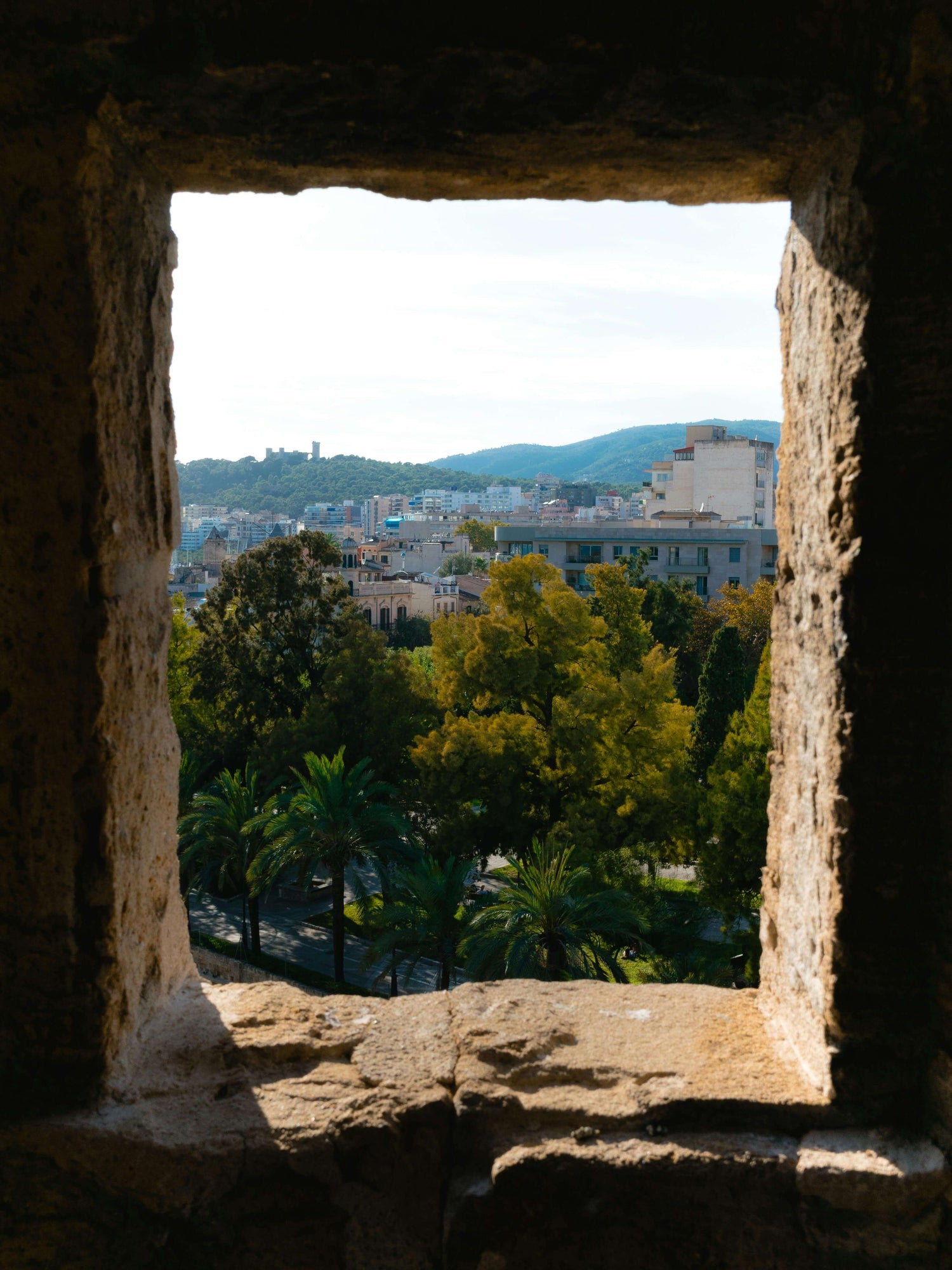 View through a Mediterranean stone window of a cityscape with buildings and greenery